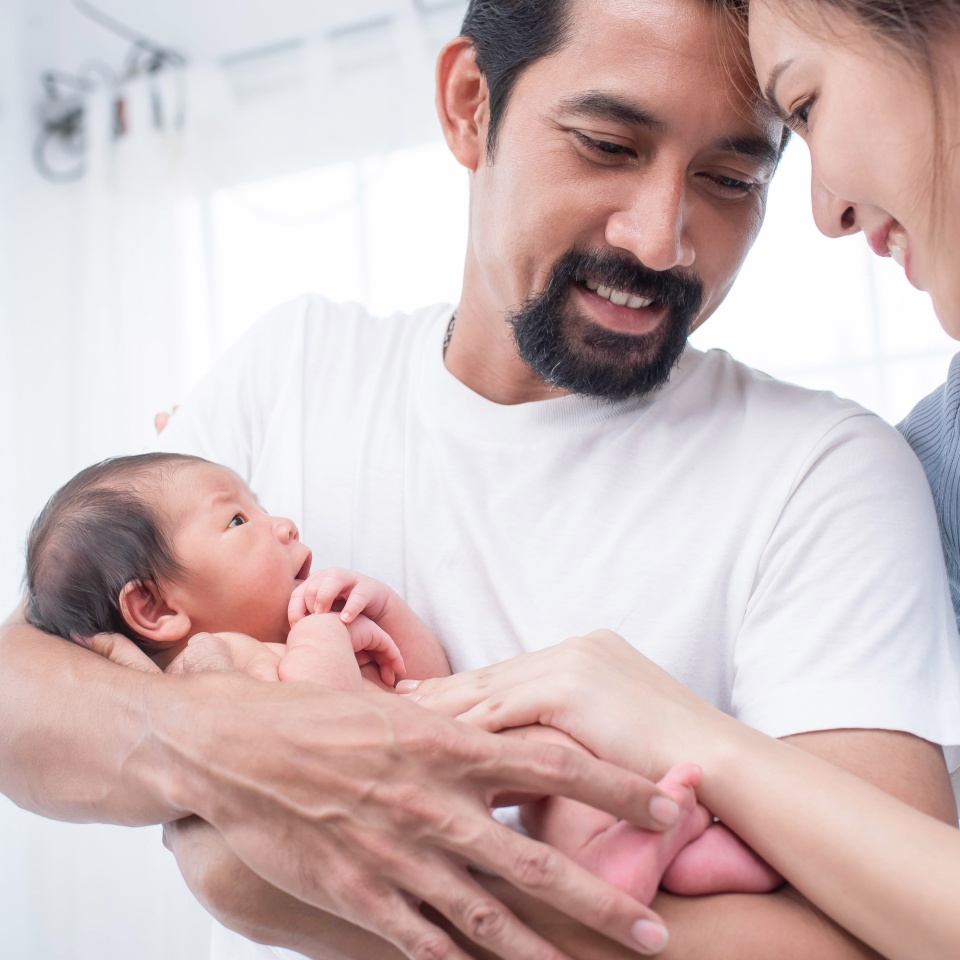 smiling mother and father holding their newborn baby at home. portrait of happy family at home, young parents holding on hands little sweet newborn baby, love and happiness concept.