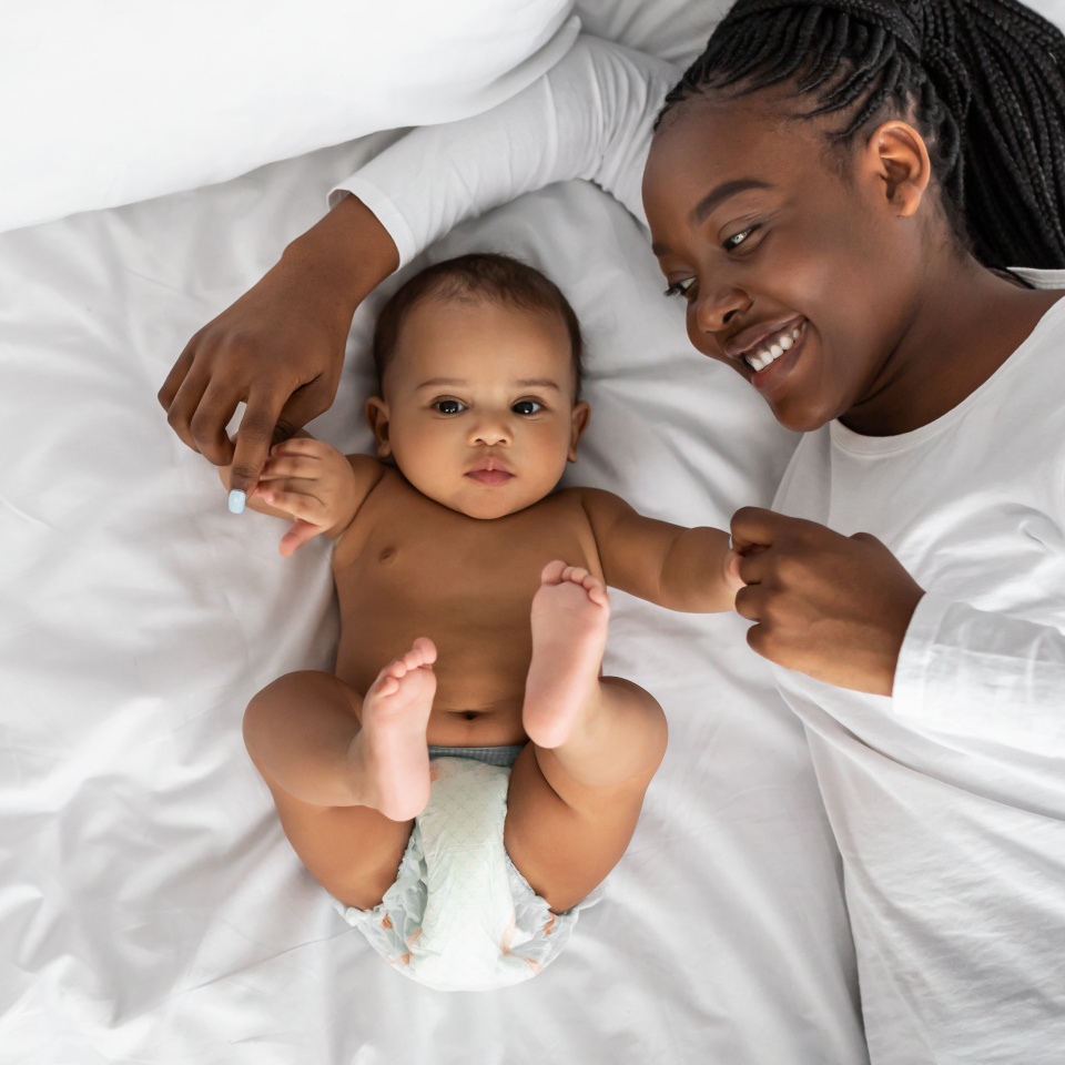 African American mom lying in bed with her cute infant
