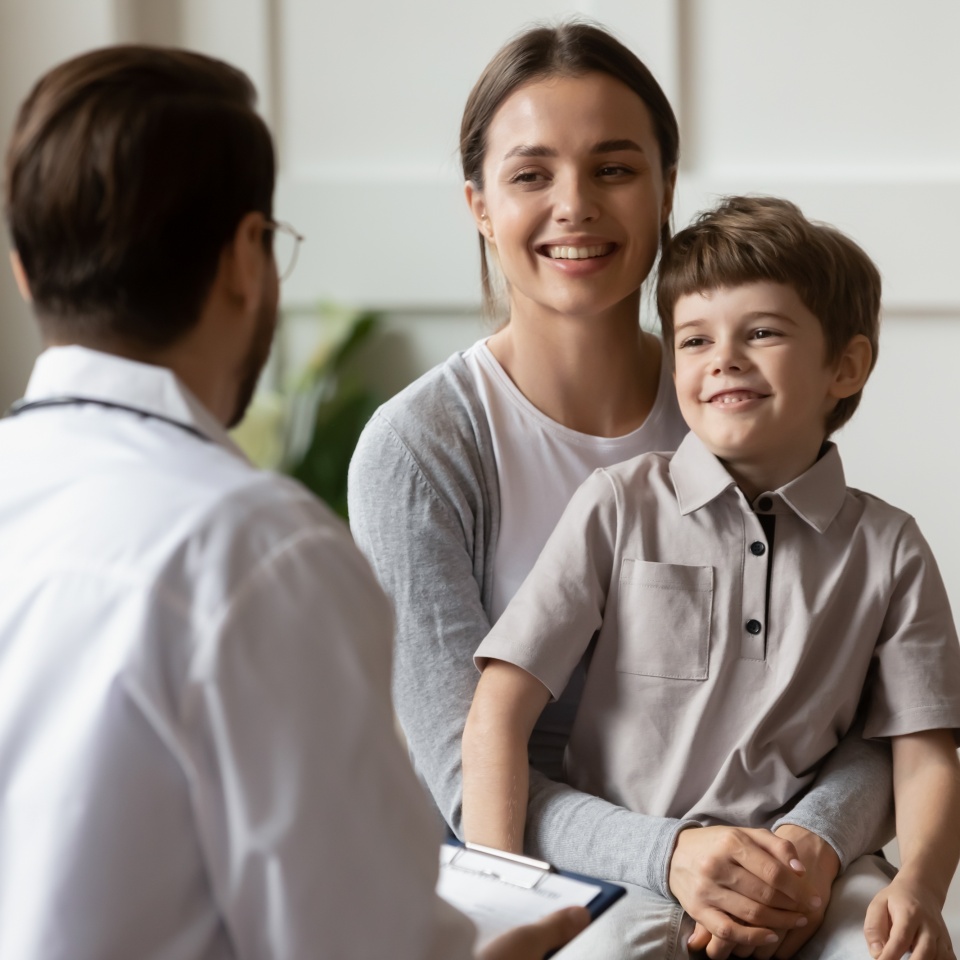 Smiling young Caucasian mother with small boy patient do checkup in private clinic with pediatrician. Happy mom and little child examine consult at doctor office in hospital. Healthcare concept.