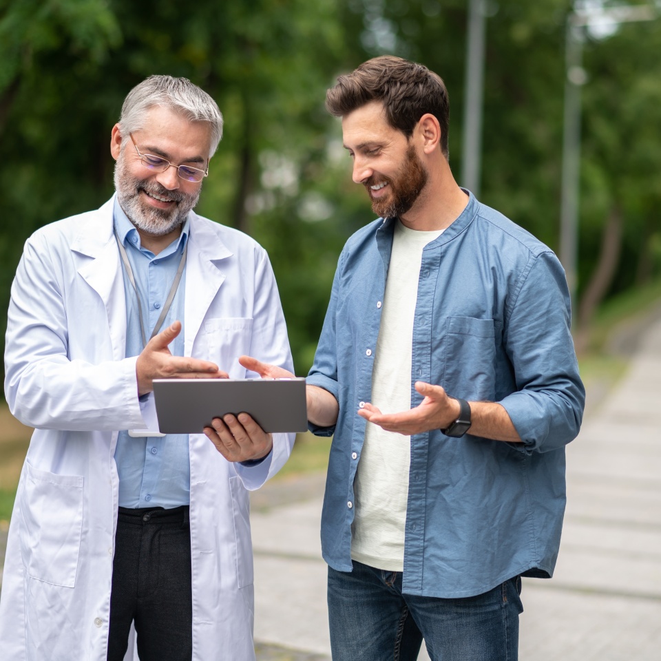 Young man talking to a mature experienced doctor in a lab coat