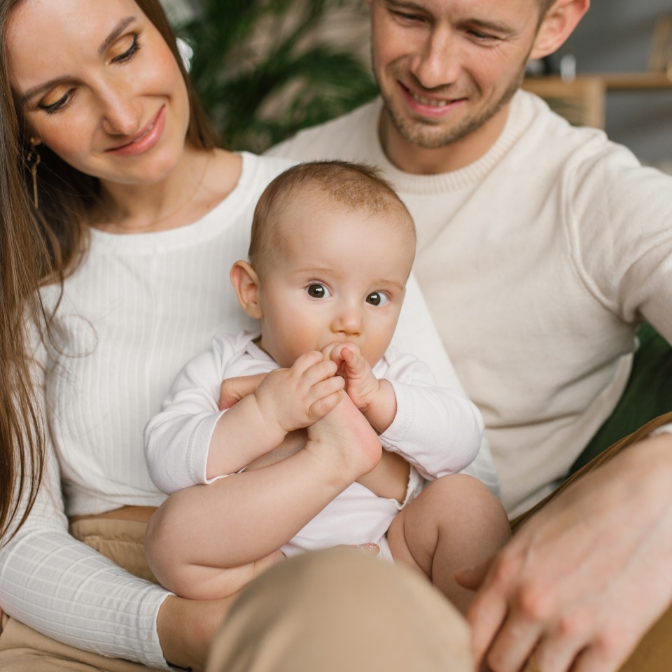 Mom, dad and six-month-old baby son in their arms spend time together in their cozy home