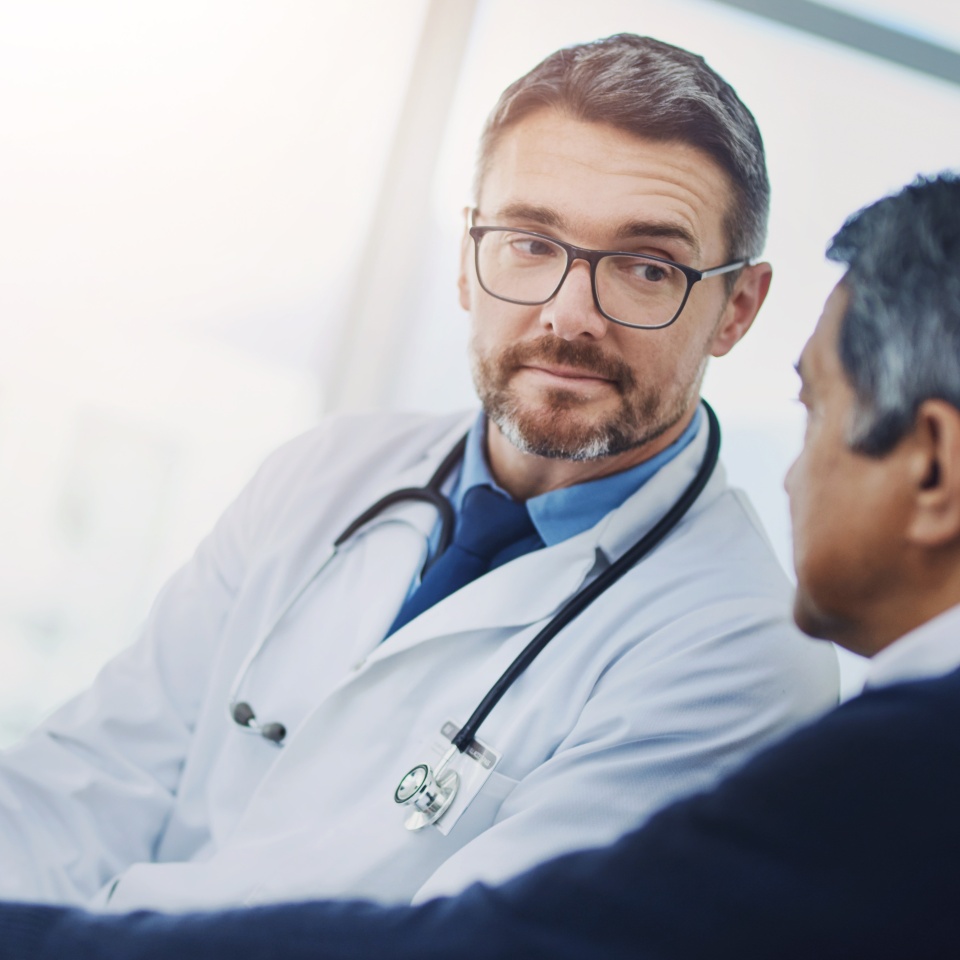 Doctor, men and tablet for consultation or checkup in clinic, talking and treatment for healthcare. Mature specialist, speaking and medical records for senior patient diagnosis, cardiology and help