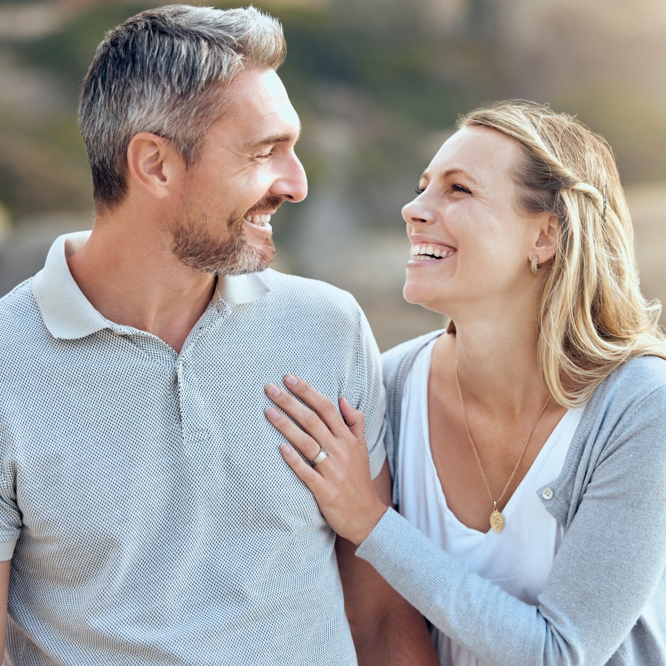 Laughing, happy man and woman at beach for love, trust and care or support for relationship. Together, couple and smile in nature for date or travel, marriage and joke or humour for outdoor adventure