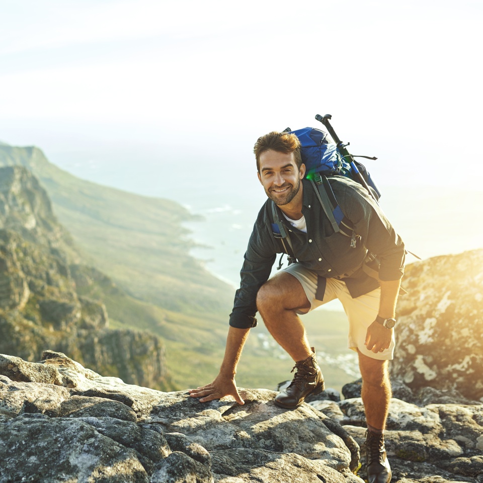 Man, climbing and mountain with portrait outdoor for fitness adventure, sports challenge and hiking travel. Male person, backpack and rocks with trekking, balance and exercise performance for explore