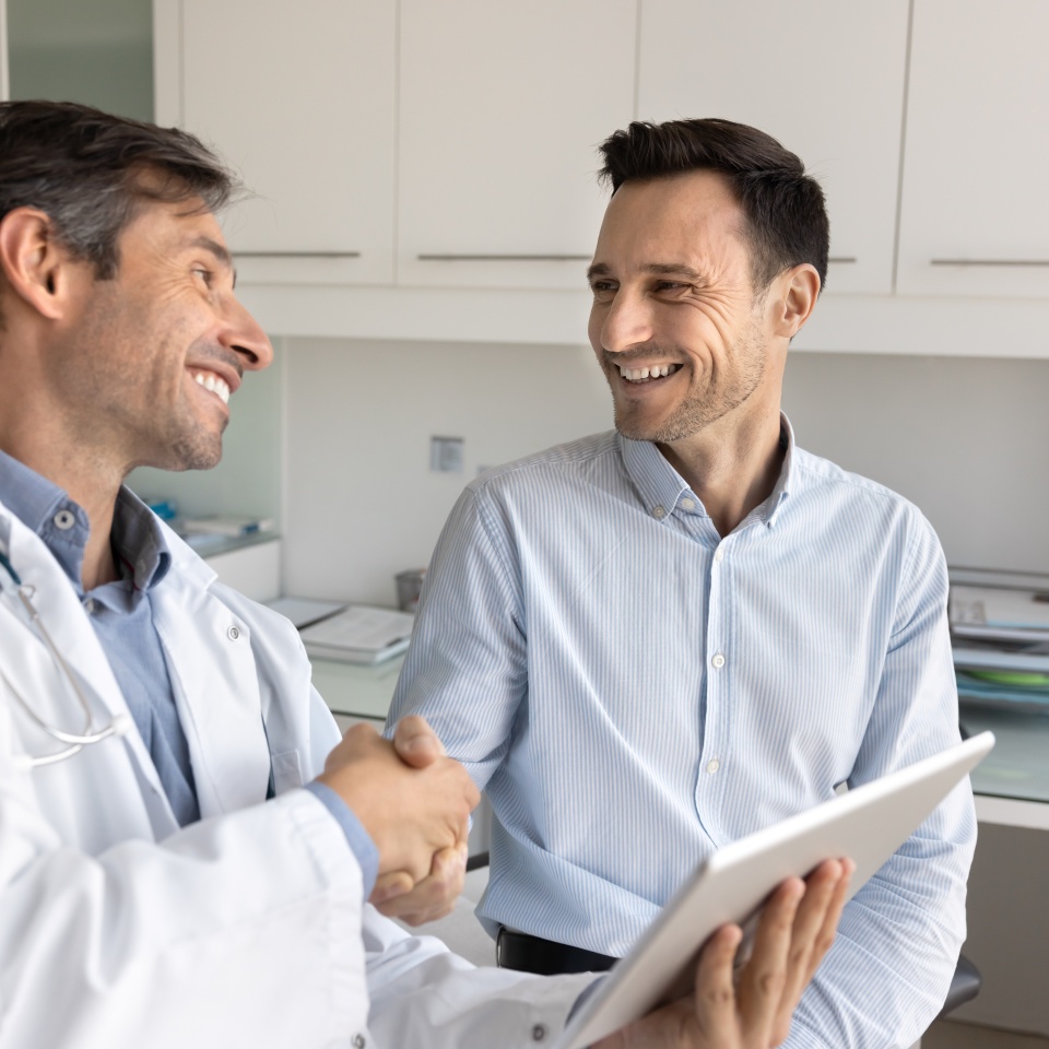 Cheerful Latin patient giving handshake to doctor with gratitude, thanking for consultation, medical checkup, recommendation. Latin practitioner shaking hand with man visiting clinic