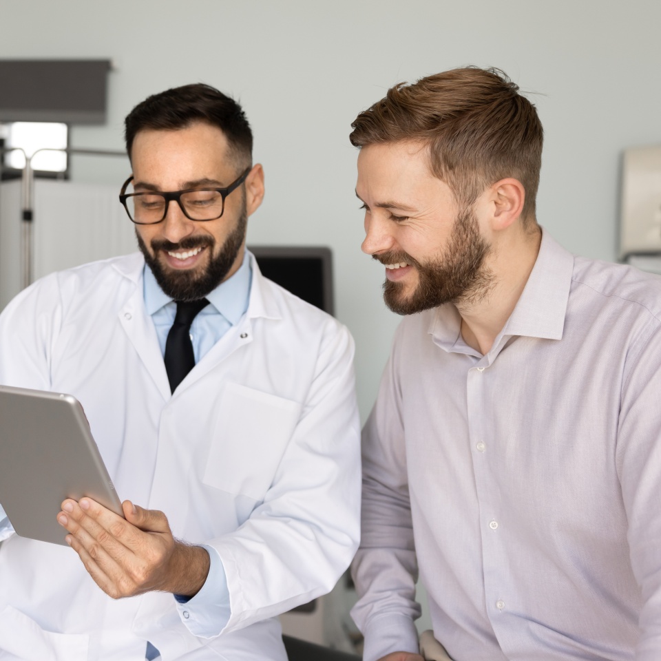 Man therapist in coat provide professional medical assistant to male patient, showing telemedicine application, or e-health platform, explain diagnosis or procedure results on tablet. Medicine, tech