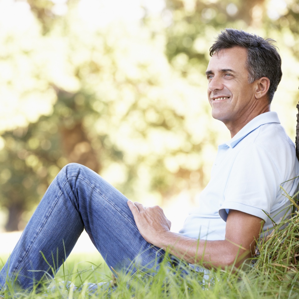 Middle Aged Man Relaxing In Countryside Leaning Against Tree