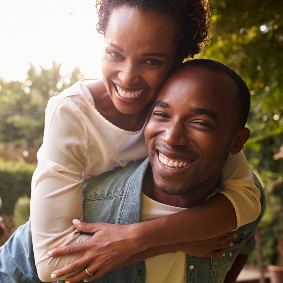 Two young adult black couples piggybacking look to camera