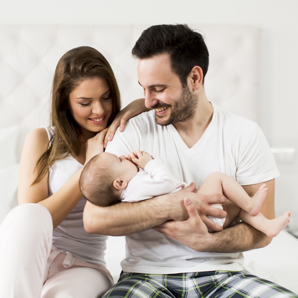 View at happy family with newborn baby on the bed in room
