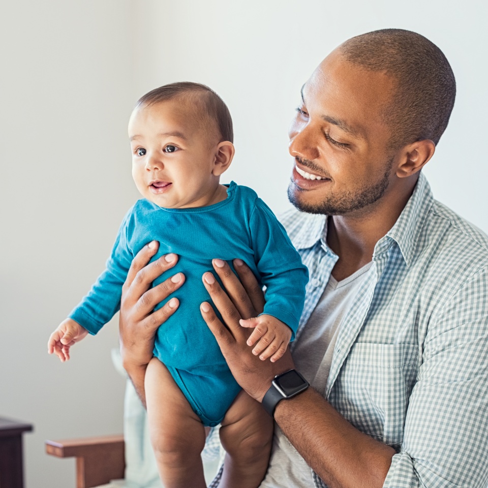 Happy black father and his baby having fun at home. Proud african father holding toddler in arms and playing. Smiling dad loving his cute son.
