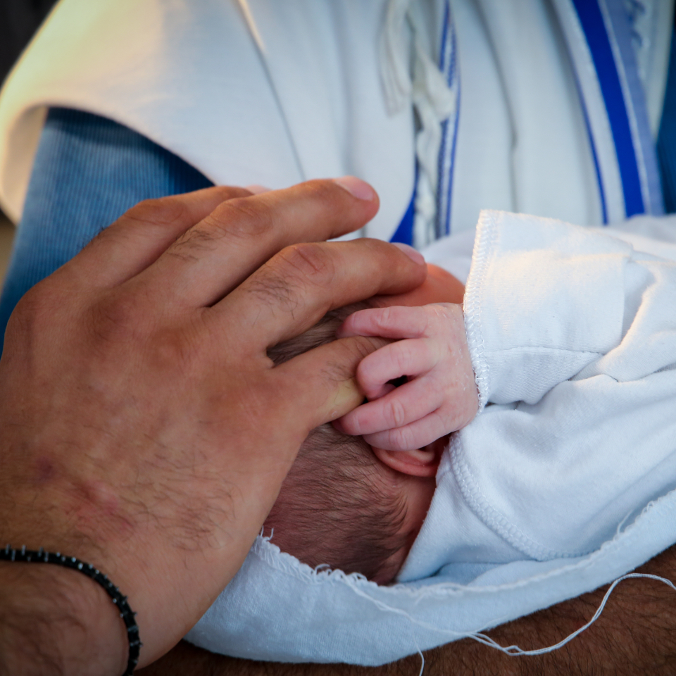 Father holds a baby's hand in a circumcision ceramony